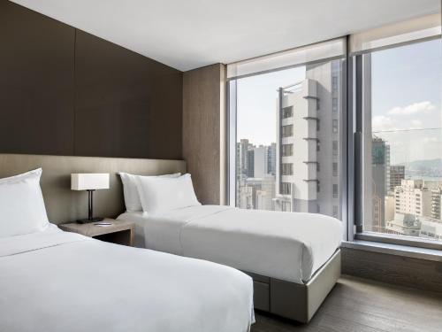 two beds in a hotel room with a large window at One96 in Hong Kong