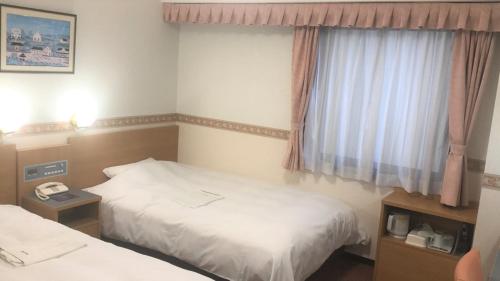 Hotel Alpha-One Takayama في تاكاياما: غرفة فندقية بسريرين ونافذة