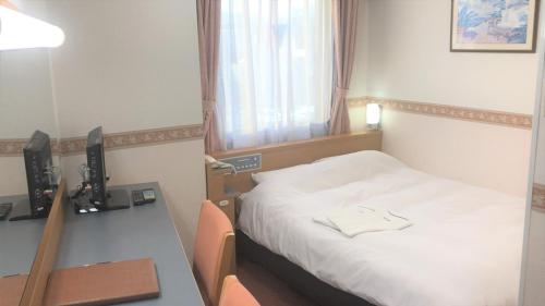 Hotel Alpha-One Takayama في تاكاياما: غرفة في الفندق بها سرير ومكتب وبه جهاز كمبيوتر