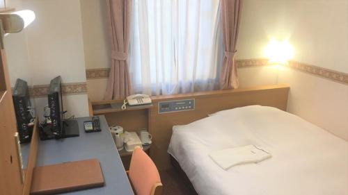 a room with a bed and a desk with a phone at Hotel Alpha-One Takayama in Takayama