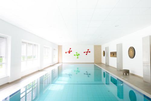 a large swimming pool with blue tile floors and a white ceiling at Zar-Hotel Vitalis in Regensburg