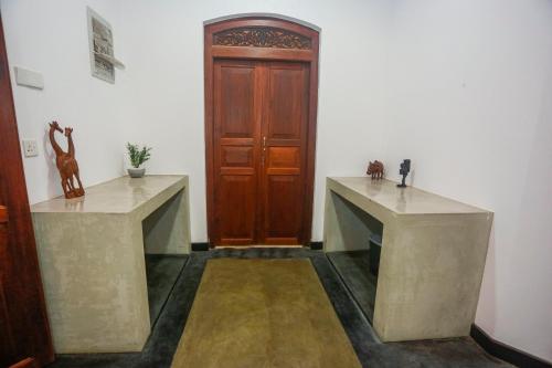 a room with two tables and a wooden door at Villa RISITHENMI in Ahangama