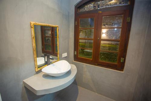 a bathroom with a sink and a mirror and a window at Villa RISITHENMI in Ahangama