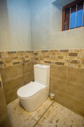 a bathroom with a white toilet in a room at Villa RISITHENMI in Ahangama