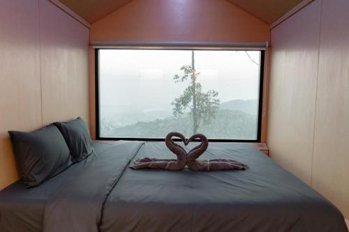 zwei Flamingos sitzen auf einem Bett vor einem Fenster in der Unterkunft Bobocabin Dieng, Wonosobo 