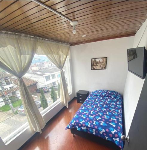 een slaapkamer met een bed en een groot raam bij Casa Guayacanes in Manizales