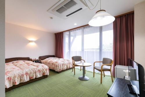 una camera d'albergo con due letti e un tavolo con sedie di Greenpia Yame a Yame