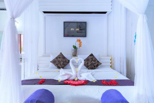 a bedroom with a white bed with two swans on it at One Bedroom Private Villa Kuta in Seminyak