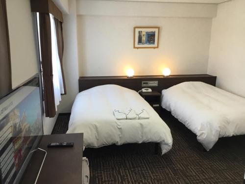 Habitación de hotel con 2 camas y TV de pantalla plana. en Hotel Alpha-One Takayama Bypass, en Takayama