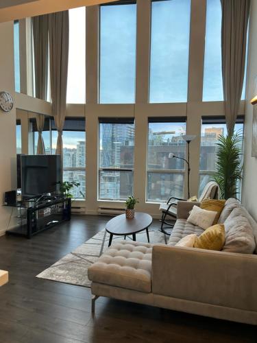 a living room with a couch and a tv at Modern top-floor 1-bedroom loft with free parking in Vancouver