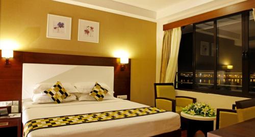 a hotel room with a bed and a desk and a window at Cochin Seaport Hotel in Cochin