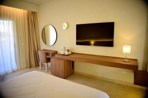 Reef Oasis Beach Aqua Park Resort في شرم الشيخ: غرفة في الفندق مع مكتب مع تلفزيون على الحائط