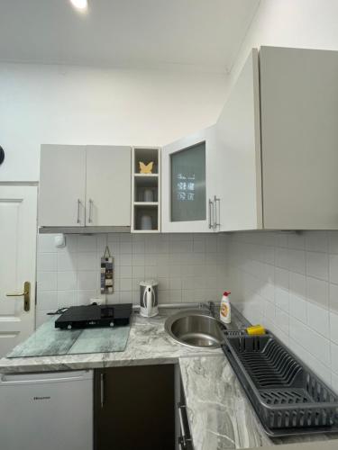 a kitchen with white cabinets and a sink at IGNIM Apartment in Subotica