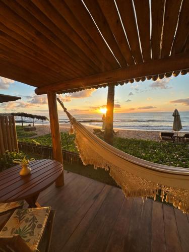 a hammock on the beach at sunset at Joju Bangalôs & Bistrô in Japaratinga