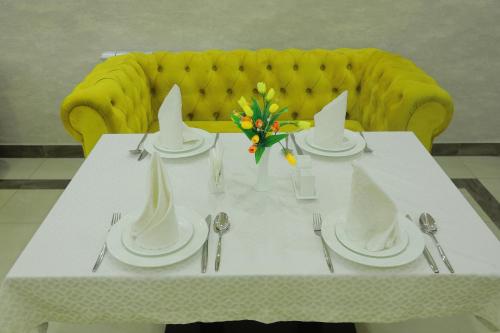 een tafel met borden en bestek en een gele bank bij Human Hotel in Tasjkent