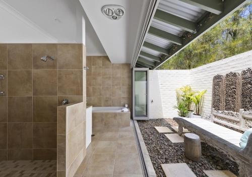 uma casa de banho com um chuveiro e um banco em Sweetacres Hunter Valley em Pokolbin