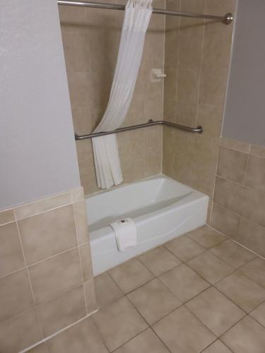 a bathroom with a bath tub with a toilet paper roll at Studio 6 Suites Hinesville, GA in Hinesville