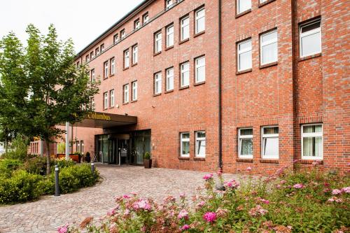 ein großes rotes Backsteingebäude mit Blumen davor in der Unterkunft Trans World Hotel Columbus in Seligenstadt