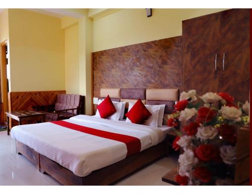 1 dormitorio con 1 cama con almohadas rojas y flores en The Mountain Paradise Hotel, Rewalsar, H.P., en Mandi