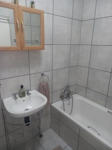 ein weißes Badezimmer mit einem Waschbecken und einer Badewanne in der Unterkunft hello honey in Kimberley