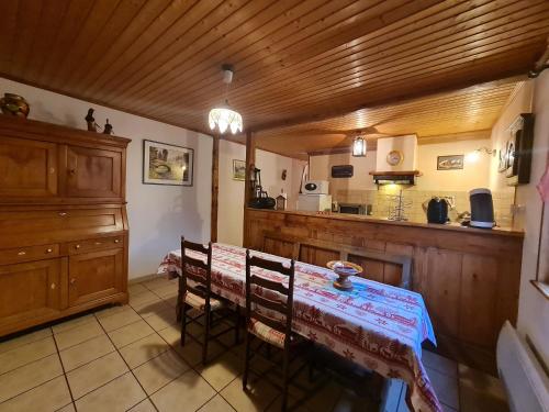 une cuisine avec une table et des chaises dans une pièce dans l'établissement Maison Vosgienne Charmante: 2 Chambres, Cheminée, Proche Gérardmer, Parfaite pour Familles et Fêtes - FR-1-589-36, à Corcieux