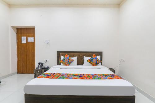 a bedroom with a large white bed with colorful pillows at FabHotel Sarovar Palace in Muthiganj