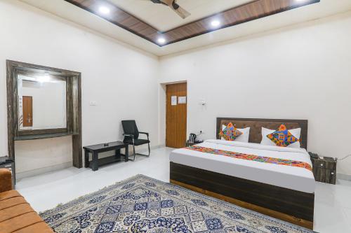Schlafzimmer mit einem Kingsize-Bett und einem Stuhl in der Unterkunft FabHotel Sarovar Palace in Muthiganj