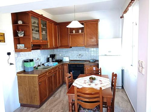 uma cozinha com armários de madeira e uma mesa com cadeiras em Holiday House with sea view in Skala Polichnitos em Skála