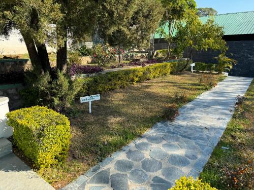 a garden with a sign in the middle of a walkway at Brij Anayra Dharamshala - A Himalayan Luxury Retreat in Dharamshala