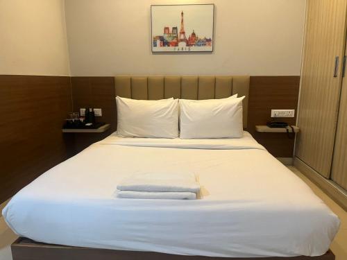 a bed in a hotel room with towels on it at Hotel Avenue Suites Near International Airport Bangalore in Bengaluru