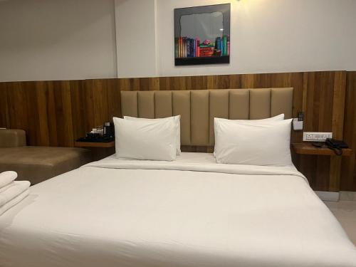 a large bed with white pillows and a mirror above it at Hotel Avenue Suites Near International Airport Bangalore in Bengaluru