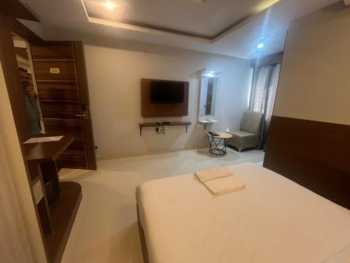 a bedroom with a bed and a tv in a room at Hotel Avenue Suites Near International Airport Bangalore in Bengaluru