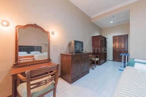 a bedroom with a dressing table and a mirror at Hotel Ayong Linggarjati Kuningan Mitra RedDoorz in Kuningan