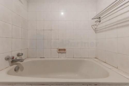 a white bath tub in a white tiled bathroom at Hotel ayong Linggarjati Kuningan Mitra RedDoorz in Kuningan