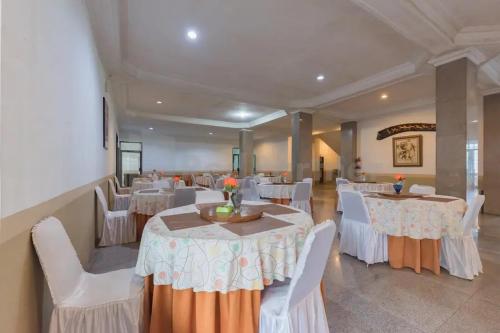 a banquet hall with white tables and white chairs at Hotel Ayong Linggarjati Kuningan Mitra RedDoorz in Kuningan