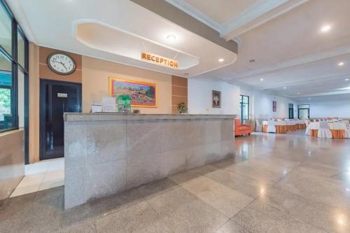 a lobby with a bar and a clock on the wall at Hotel Ayong Linggarjati Kuningan Mitra RedDoorz in Kuningan