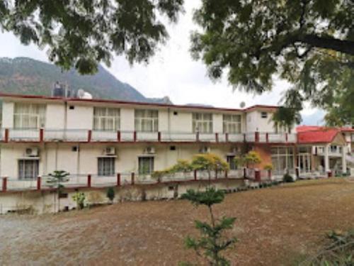 a large white building with a tree in front of it at River view resort Uttarkashi in Uttarkāshi