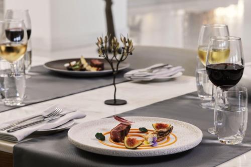 a plate of food on a table with wine glasses at Domes Miramare, a Luxury Collection Resort, Corfu - Adults Only in Moraitika