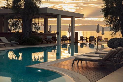 a swimming pool with lounge chairs and a table at Domes Miramare, a Luxury Collection Resort, Corfu - Adults Only in Moraitika