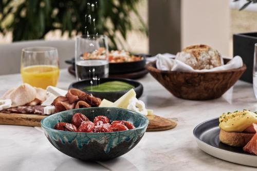 a table with plates of food and bowls of food at Domes Miramare, a Luxury Collection Resort, Corfu - Adults Only in Moraitika