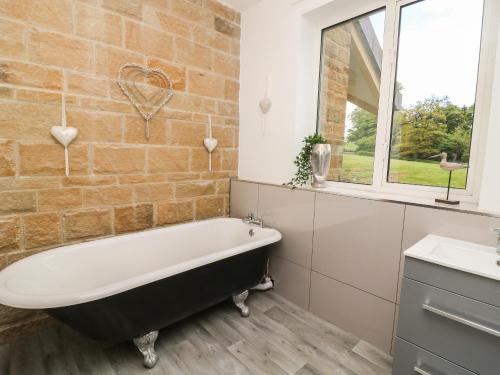 a bathroom with a bath tub and a window at Myddelton Grange in Ilkley