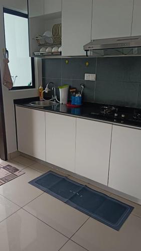 eine Küche mit weißen Schränken und einer schwarzen Arbeitsplatte in der Unterkunft Desaru Utama Residence Homestay in Bandar Penawar