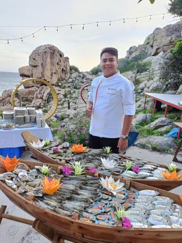 a man standing in front of a table with a table at Khu du lịch Hang Rái - Ninh Thuận in Thôn Thái An