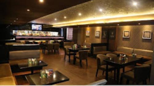 ein Restaurant mit Tischen und Stühlen und eine Bar in der Unterkunft Hotel Blue Saphire Countryside Haldwani in Haldwani-Kathgodam