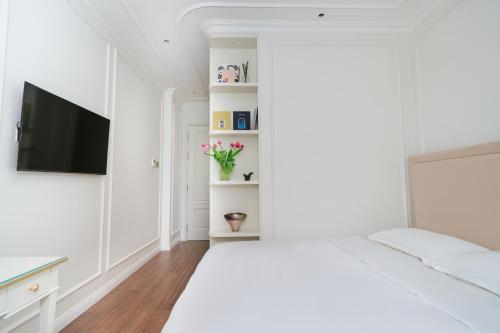 a white room with a bed and a flat screen tv at The Nguyens - Pink Church View in Ho Chi Minh City