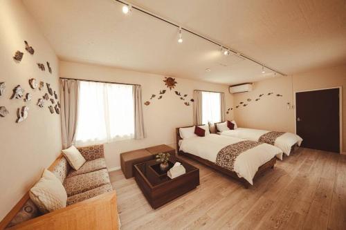 a bedroom with two beds and a couch in it at 『てぃぐまの宿』地平線まで見渡せる圧巻の屋外テラスビュー！300余年の歴史ある壺屋焼がご堪能出来る宿 in Miyako Island