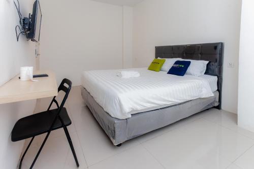 1 dormitorio con 1 cama con silla y escritorio en Urbanview Hotel Priority Samarinda by RedDoorz en Samarinda