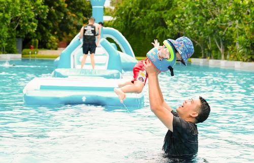 un hombre sosteniendo un bebé en una piscina en SO/ Sofitel Hua Hin en Cha Am