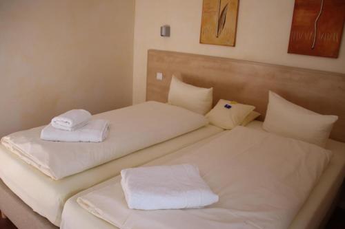 two beds in a room with white towels on them at 4 Sterne Apartment Hühnergott mit Terrasse und Sauna in Lobbe