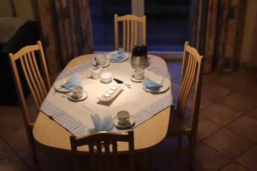 una mesa con un mantel blanco con platos en 4 Sterne Apartment Mauerschwalbe mit Balkon, en Lobbe